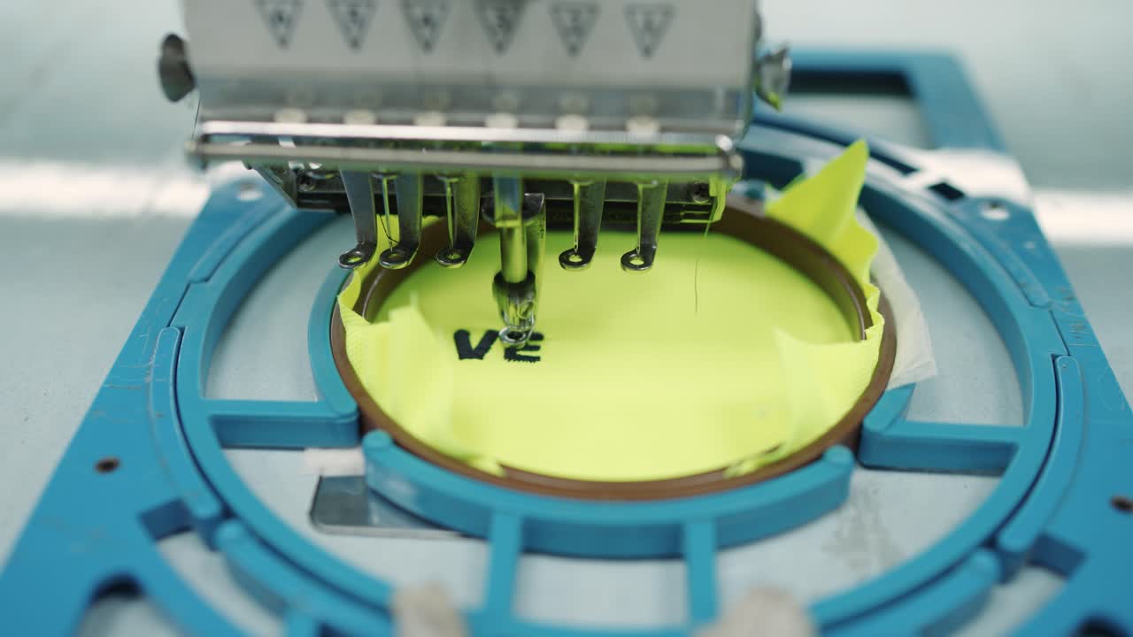 Industrial Embroidery Machine, Automated Sewing of Text on Bright Yellow Fabric