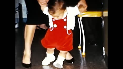 little girl in red dress standing next to man. circa usa - 1970s: a little girl dressed in a red dress is seen standing next to a man in this archival photograph from the 1970s in the usa.
