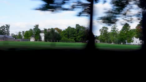 View-from-the-car-window-of-the-roadside-with-green-vegetation-with-houses-on-a-cloudy-day