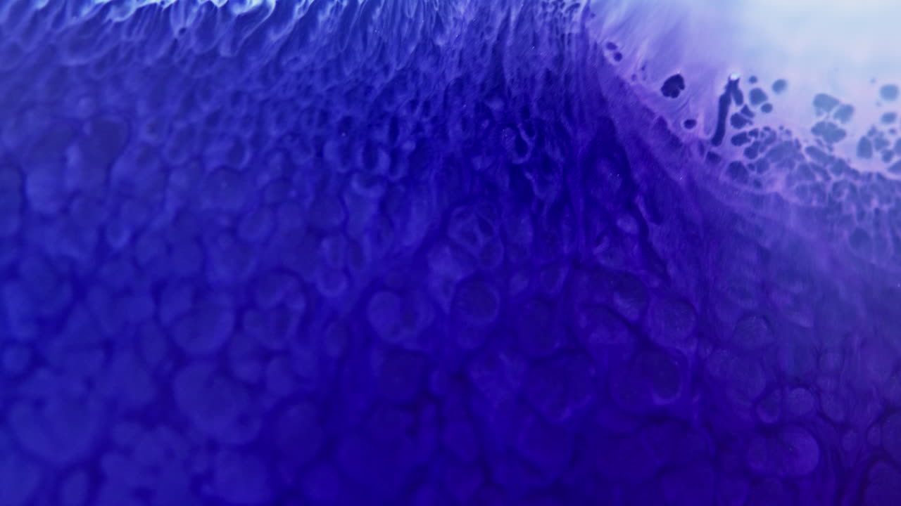 Encre violette vibrante tourbillonnant dans l'eau, créant des motifs et des textures abstraits hypnotisants