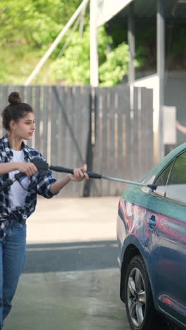 mujer lavando un coche azul en un lavado de coches de autoservicio