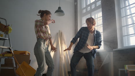 Cheerful-couple-celebrating-indoors.-Happy-family-dancing-in-renovation-house.