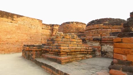 Antiguos-Muros-De-Piedra-Con-Ladrillos-Rojos-En-Los-Restos-Arqueológicos-Budistas-De-Sarnath,-Varanasi,-India,-Con-Tiro-Bajo-Para-Caminar