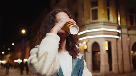 Chica-Joven-Feliz-Y-Sonriente-Disfrutando-De-Un-Café,-Una-Bebida-Caliente,-Relajándose-Y-Tomando-Un-Descanso-En-La-Calle-De-La-Ciudad-De-Noche