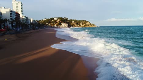 Scenic aerial reveals wave patterns along urban beach of Lloret de Mar, Spain