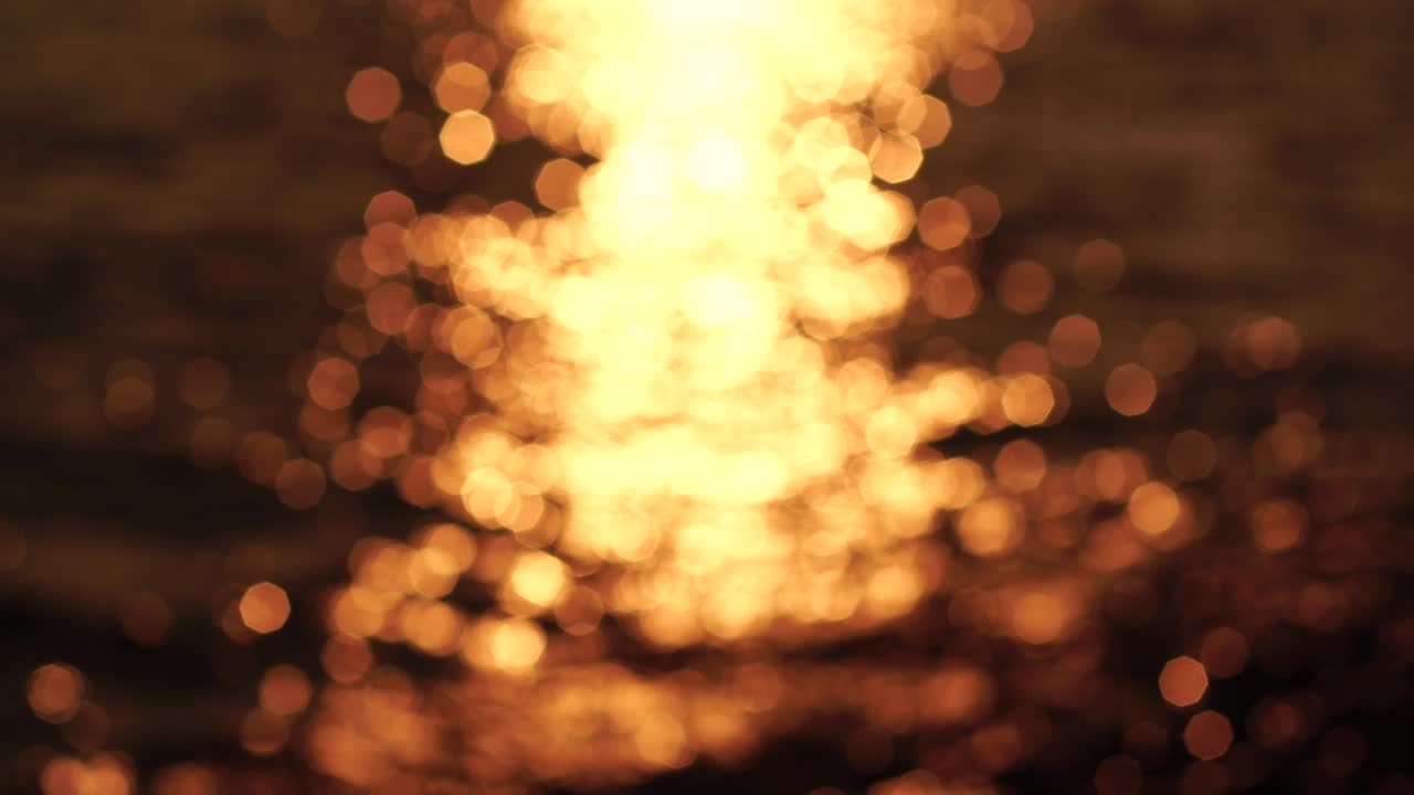 naturaleza abstracta verano océano puesta de sol fondo marino. pequeñas olas en la superficie del agua en movimiento borrosas con luces bokeh del amanecer. vacaciones, vacaciones y concepto de fondo recreativo. cámara lenta