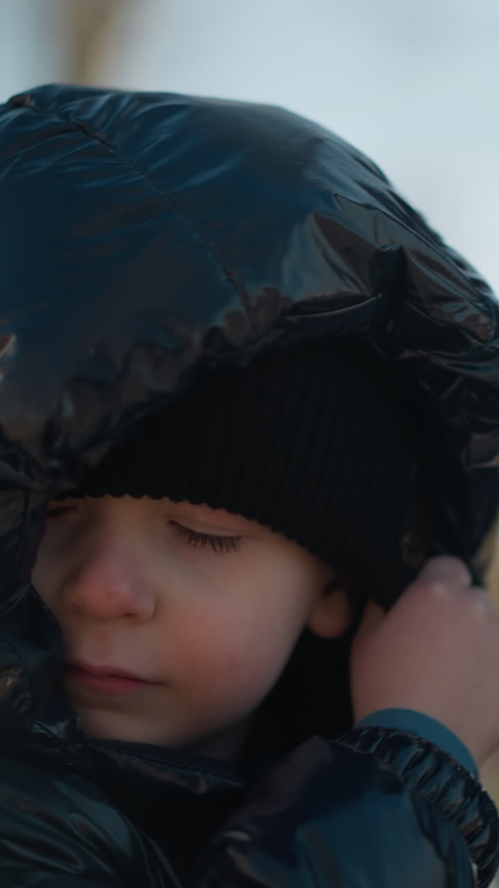 야외에서 는 동안 손을 잡고 있는 아버지와 아들의 클로즈업, 반이는 검은색 재과 검은색 베니를 입은 아이가 머리 워머를 조정하는 것을 볼 수 있습니다.