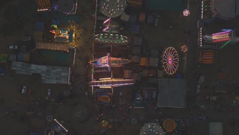 top down aerial drone shot of an indian amusement park , ferris wheel and different rides at night lighting at gwalior trade fair, india