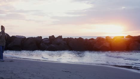 mujer caminando por una playa al atardecer