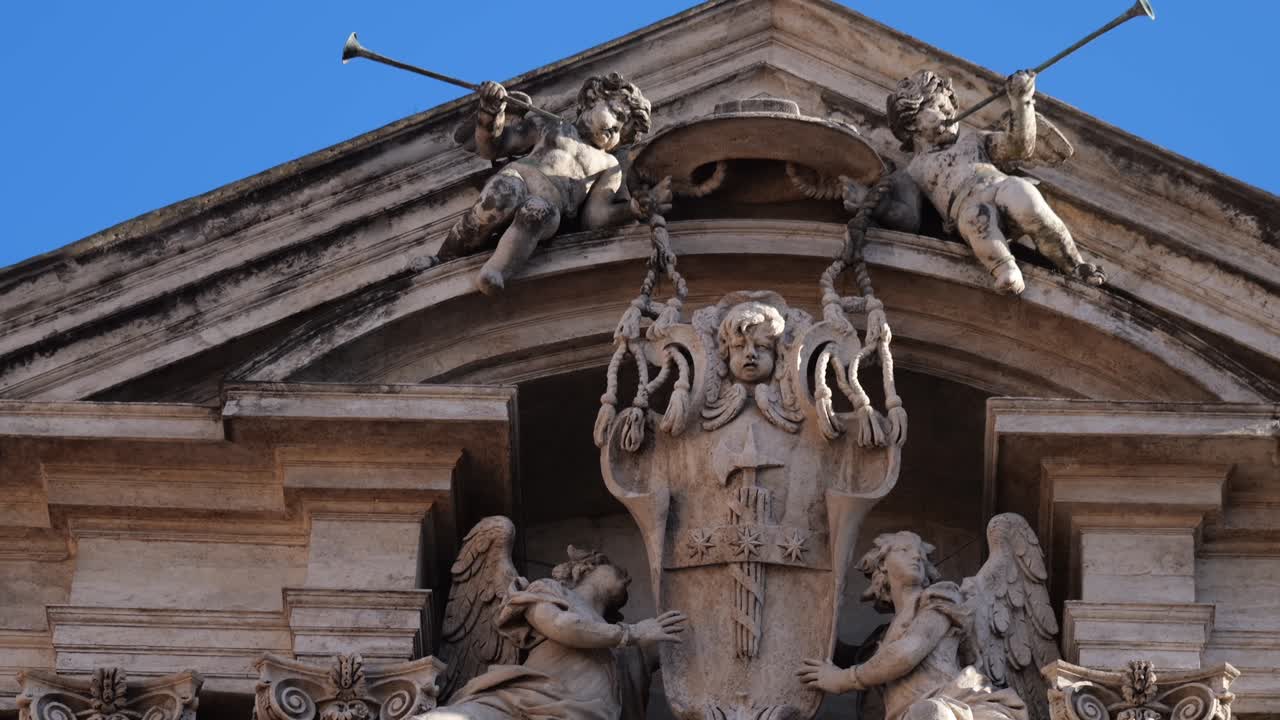 Close-up of angel sculptures holding a coat of arms on the Trevi Fountain in Rome, Italy, framed by ornate baroque columns and detailed architectural carvings.