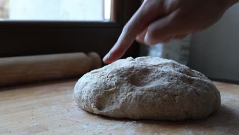 checking the consistency of the homemade pizza with wholemeal flour, shallow depth of field and soft natural light, close up shot