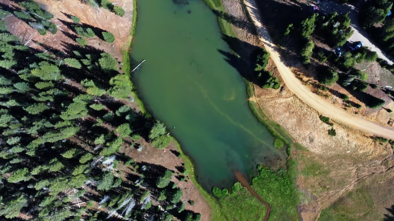 hermoso dron aéreo arriba ojo de pájaro tiro giratorio de un pequeño arroyo rodeado por un campo de hierba que conduce al lago del embalse del prado de anderson hasta el cañón del castor en utah en un cálido día de verano