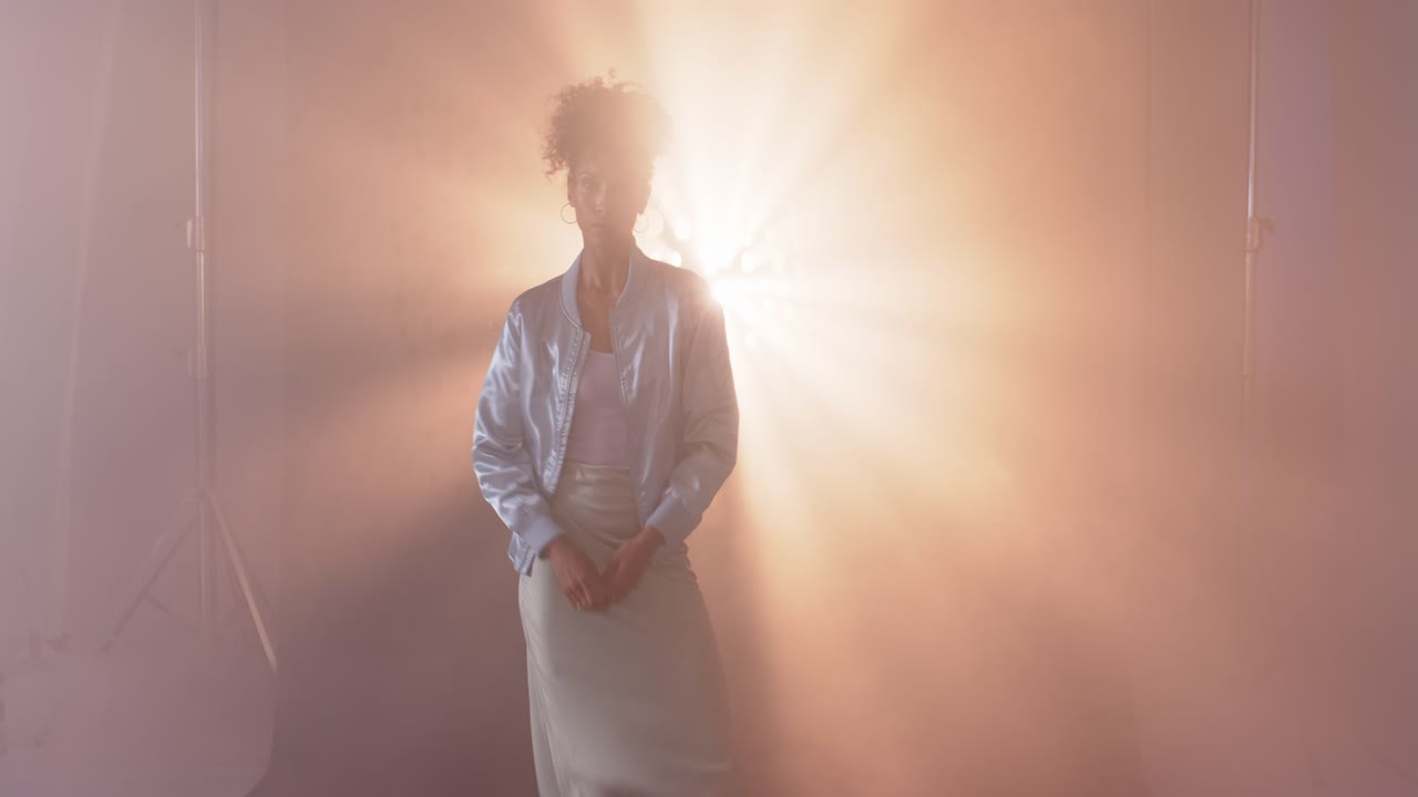 Donna elegante in posa in uno studio fumoso con retroilluminazione drammatica