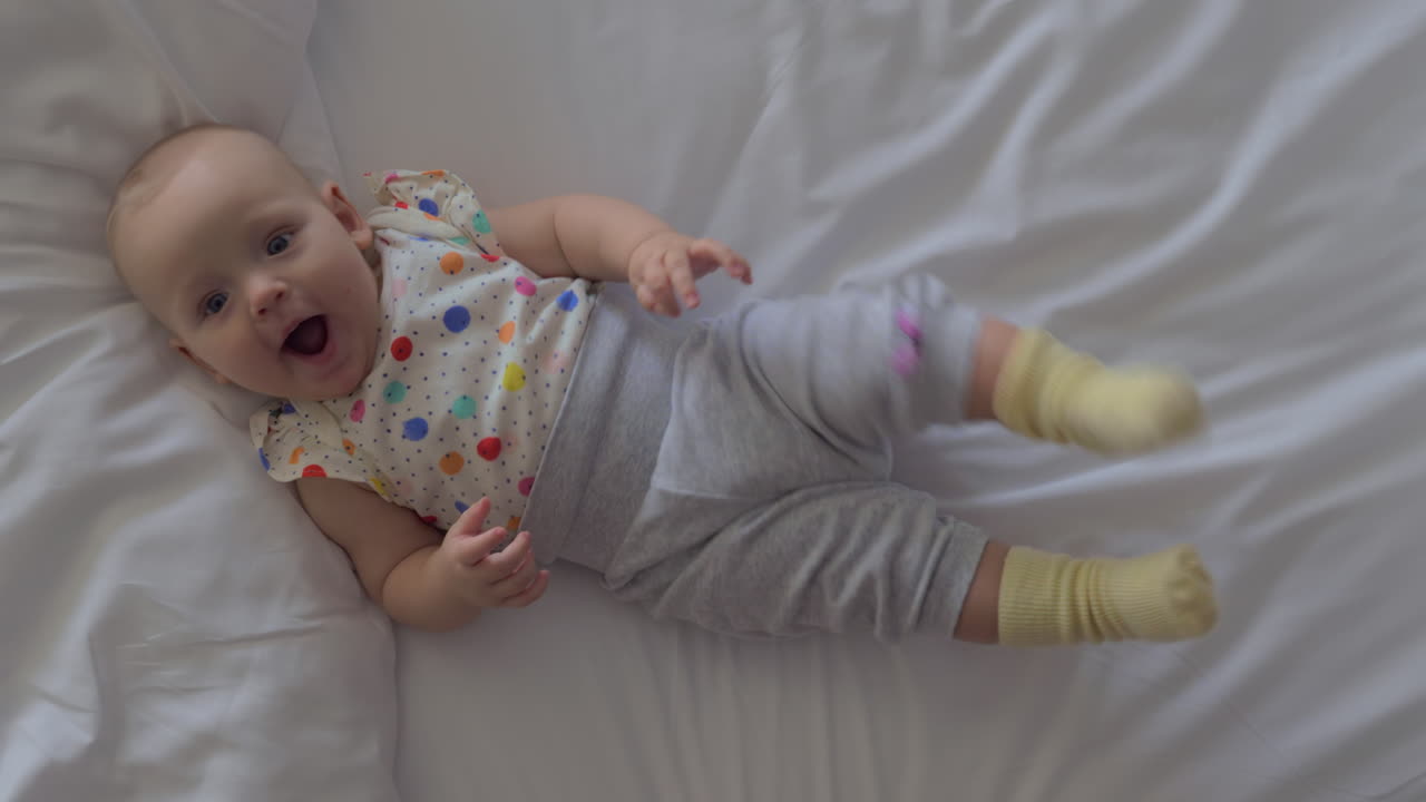 una sonriente niña de seis meses acostada en una cama