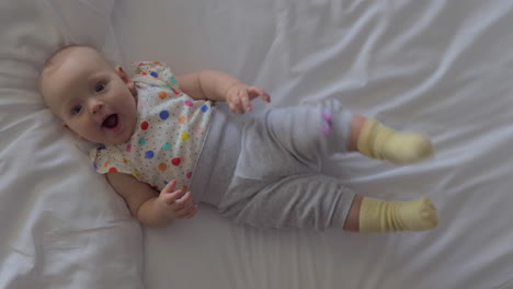 a smiling six months baby girl lying on a bed