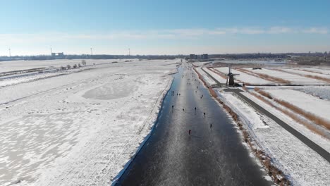 Aerial-footage-of-people-ice-skating-on-frozen-canal,-Netherlands,-winter-scene