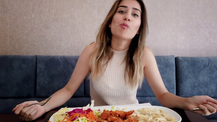 Slow motion:Beautiful young girl eats chicken food with a big enjoy in a restaurant or cafe while sitting