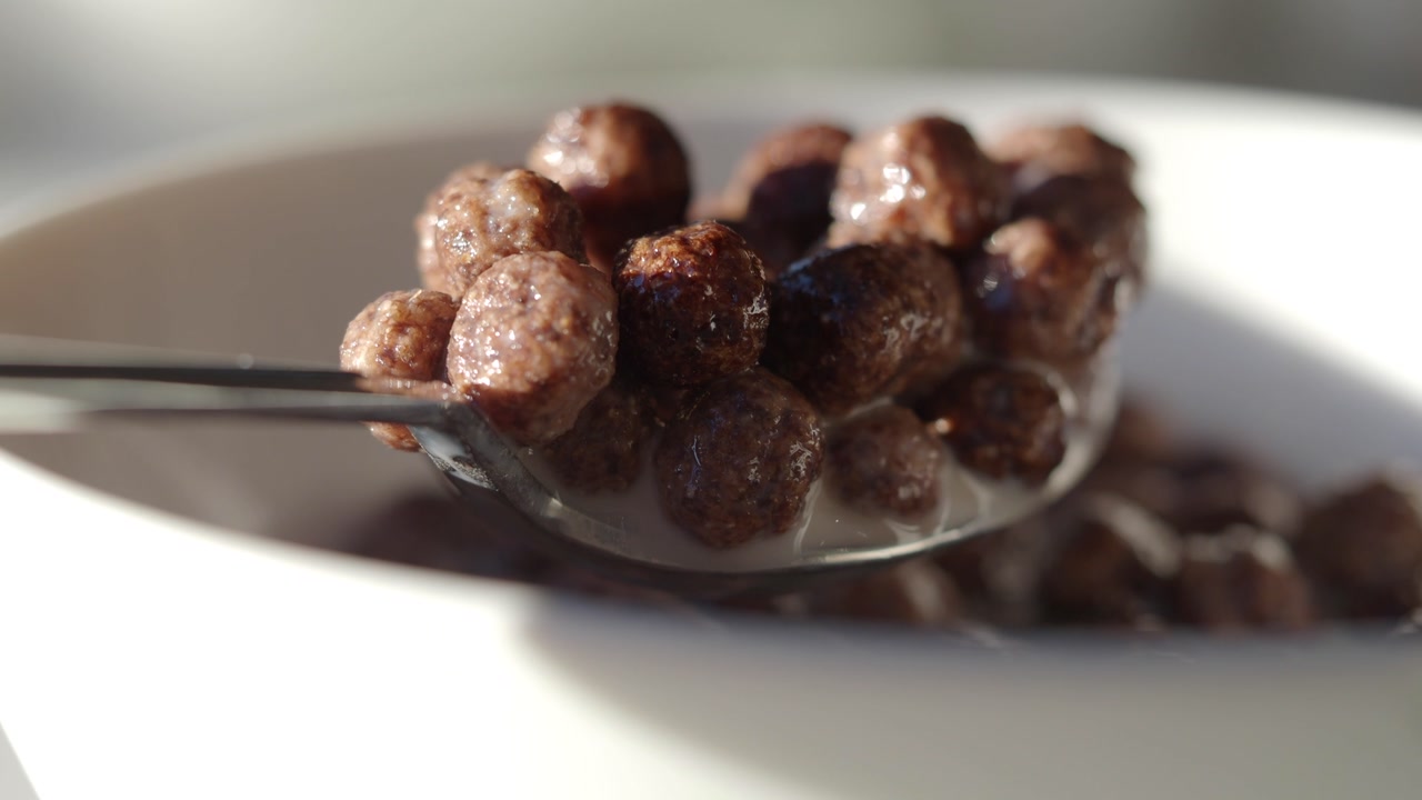 Close-up of Chocolate Cereal Balls with Milk on a Spoon