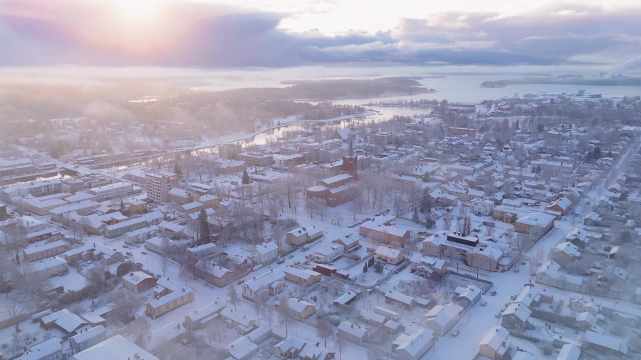 Drone sisin içinden yükselerek bir gün doğumu ve Uusikaupunki şehrini ortaya çıkarıyor. Pastel renkler, güzel 4k