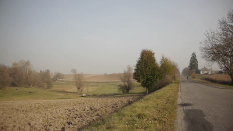 Scooter-Montando-Una-Pequeña-Carretera-Vacía-En-Un-Campo-Soleado