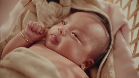 gentle focus transition on newborn in towel resting peacefully smiling on wooden cradle natural warm light , family happy moment