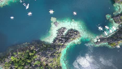 tour boats arriving scenic twin lagoon in coron philippines, bird’s eye aerial