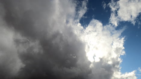 Sun-shining-through-dissipating-heavy-grey-storm-clouds,-Time-Lapse