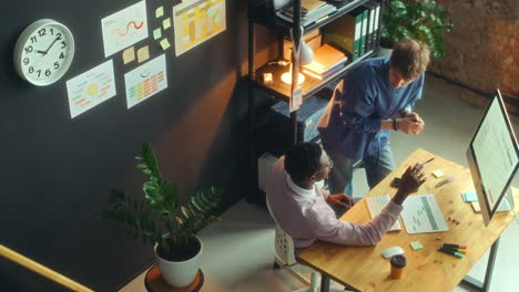 two colleagues discussing business presentation on computer in office