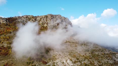 toma de un dron de un pico de montaña rocoso cubierto de niebla en un día soleado