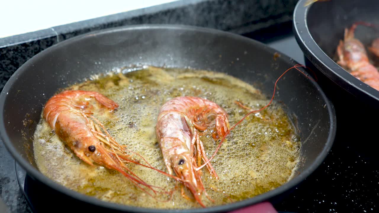 Tweezers removing prawns from pan with boiling oil