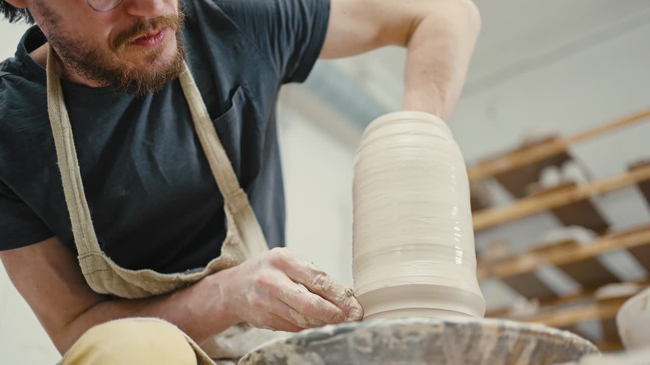 fotografía de cerca de un artista alfarero masculino esculpiendo un jarrón de cerámica en la rueda del alfarero, en cámara lenta, vista de abajo