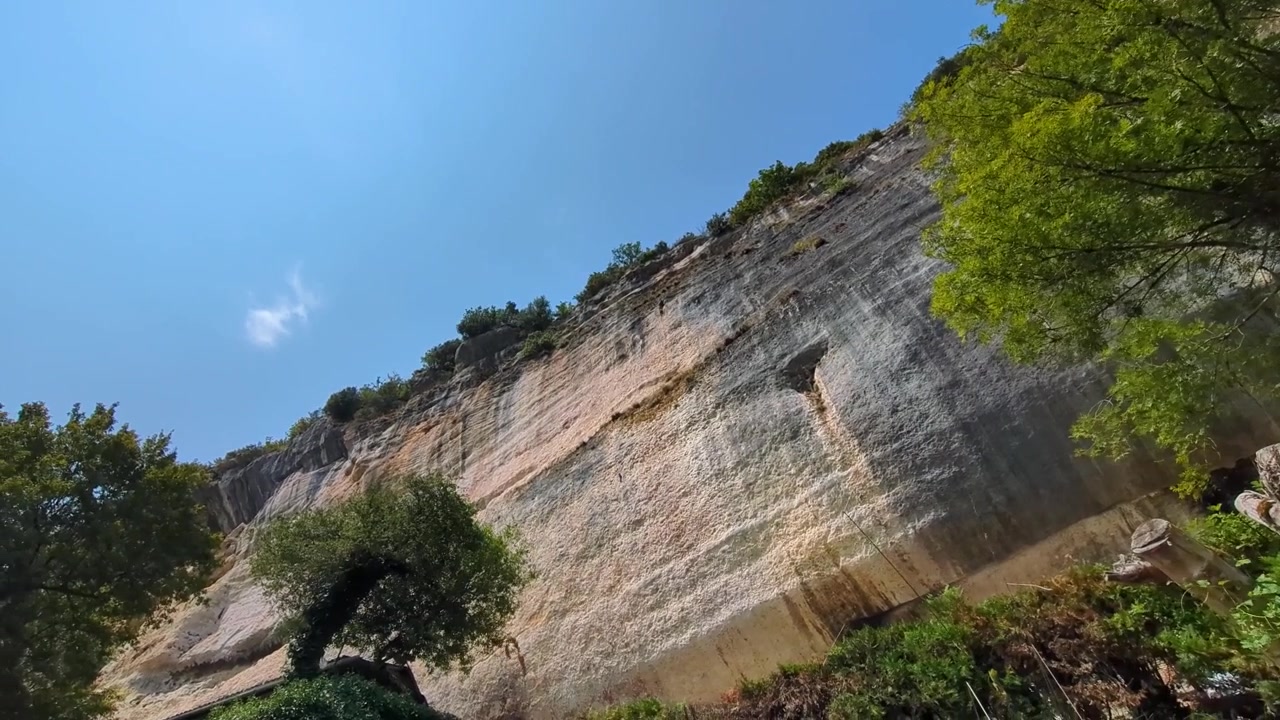 Ripresa panoramica rotante attraverso una scogliera montuosa preistorica ed erosa con alberi in cima in Dordogna, Francia, Europa 4K