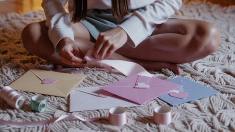 woman crafting personalized envelopes with ribbons and hearts