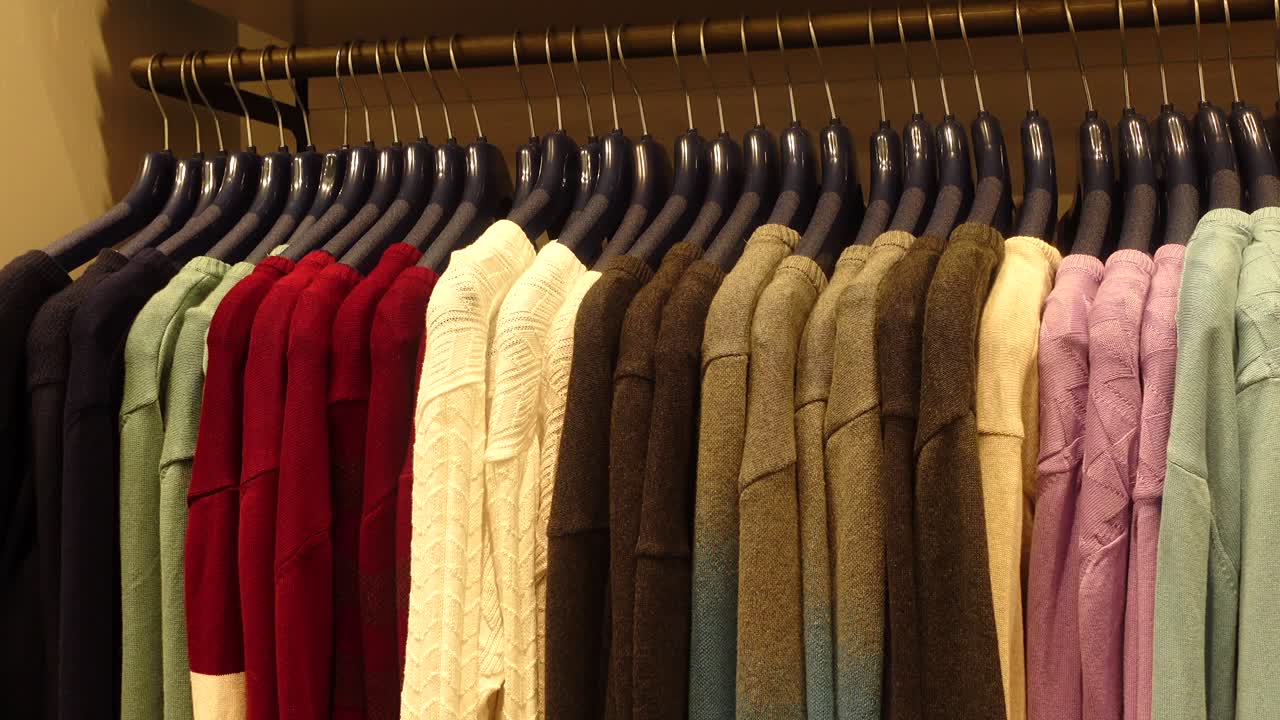 옷 가게 에 있는 다채로운 스웨터 의 랙