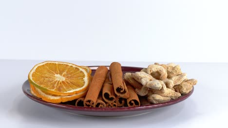 assortment of orange, cinnamon and ginger on plate against white background