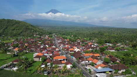 drone flying over a small village with a volcano in the background