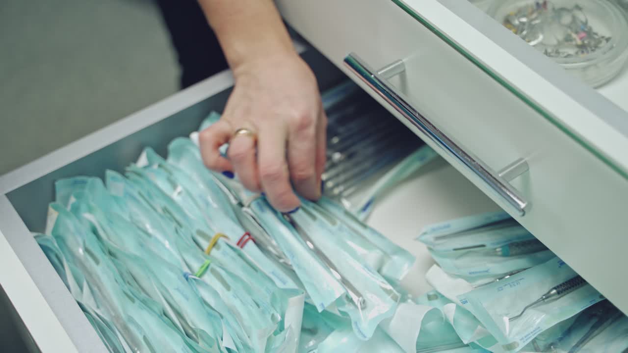 Detail of hand taking out sterile dental tools in medical clinic. Hands in latex gloves takes instruments from drawer. Dentist concept. Close-up