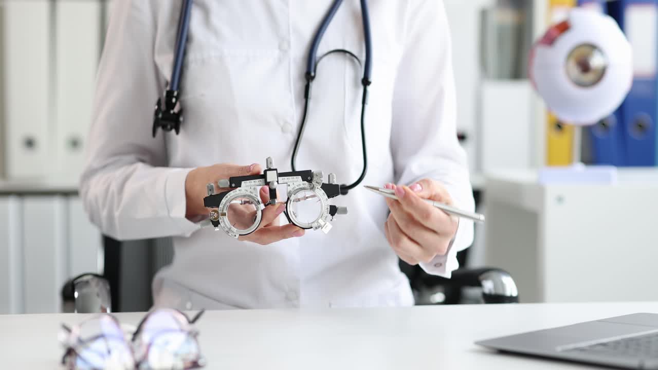 Oftalmólogo muestra gafas instrumentales para adaptar lentes y un modelo anatómico del ojo