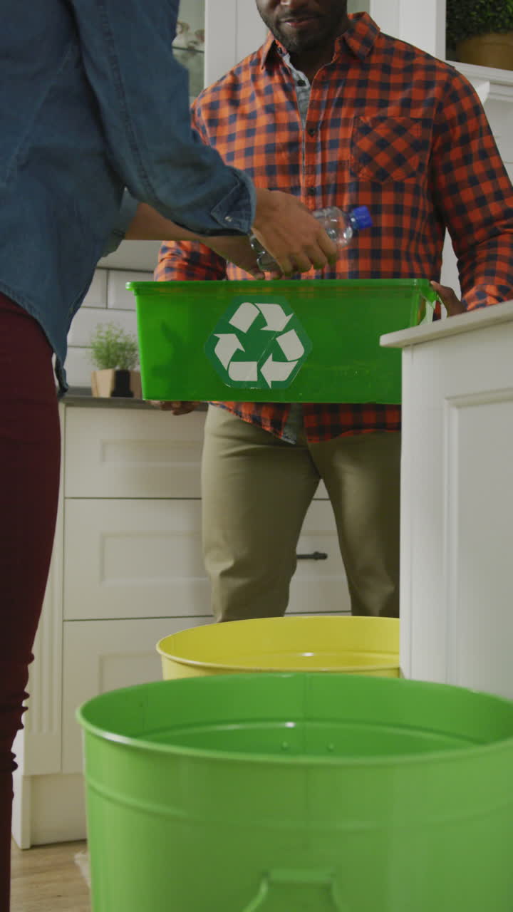 Vertical video of diverse couple segregating waste at home