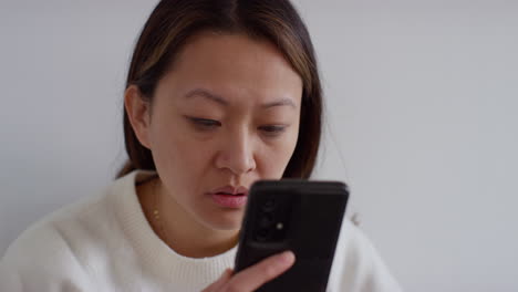 close up of stressed anxious woman at home reacting to internet or social media news message or story on mobile phone