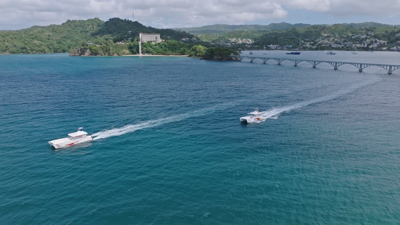 barcos navegando fuera de la bahía de samaná con el puente de cayo samaná al fondo.