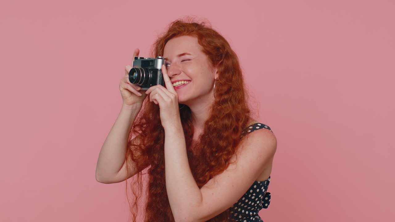 joven mujer pelirroja fotógrafa turística tomando fotos con cámara retro y sonriendo, vacaciones vacaciones