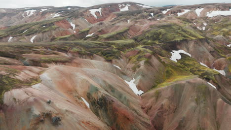 parches de nieve en las montañas de colores pastel de landmannalaugar highlands, islandia