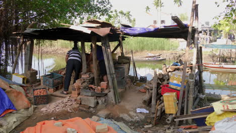 wide view of potters removing clay figurines placing into bins by beautiful riverside, than ha hoi an vietnam