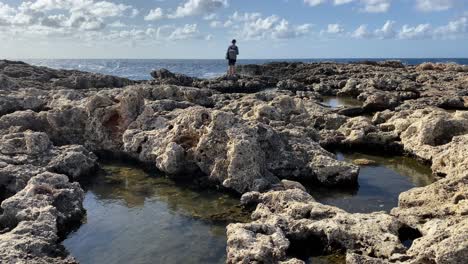 Junger-Weißer-Reisender,-Der-Meereswellen-Genießt,-Die-Die-Felsige-Malta-küste-Treffen