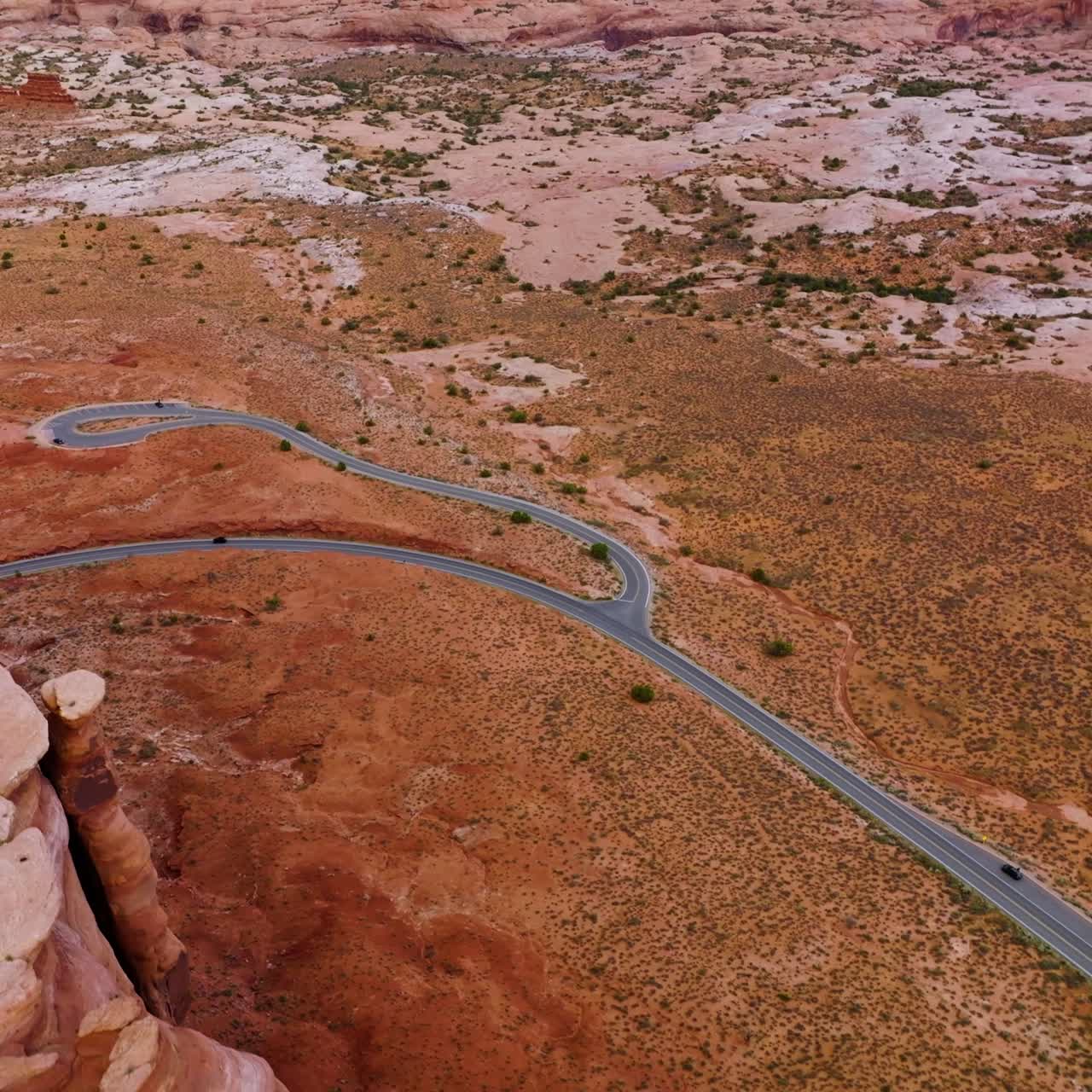 Rounded smooth rocks of canyons in National Arches Park, Utah, USA. Lonely car following the road in the deserted valley. Top view