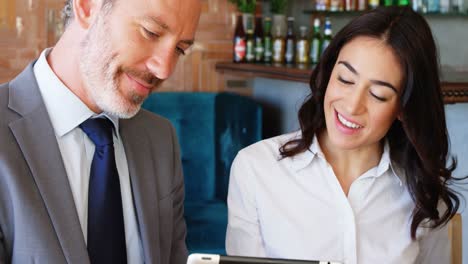 Woman-and-businessman-interacting-with-each-other-while-using-digital-tablet