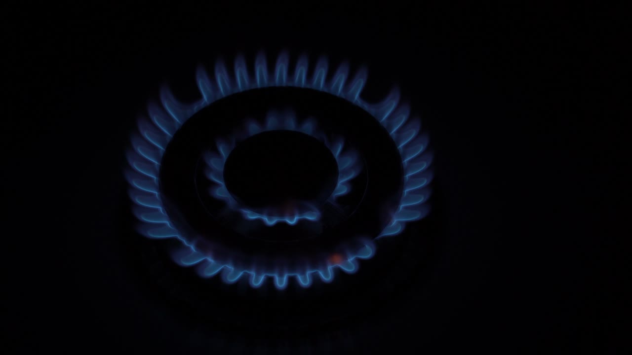 на черном фоне на кухонной домашней газовой плите горит газовый горелок и медленно гасит. концепция энергетического кризиса. прекращение газоснабжения. без людей. верхний вид. 4k.