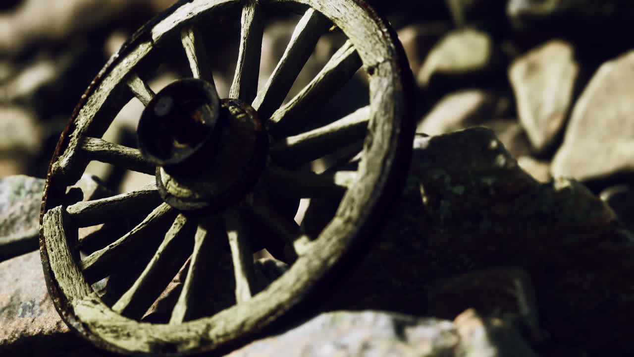 Old wooden wheel resting on rocky ground under soft light in nature