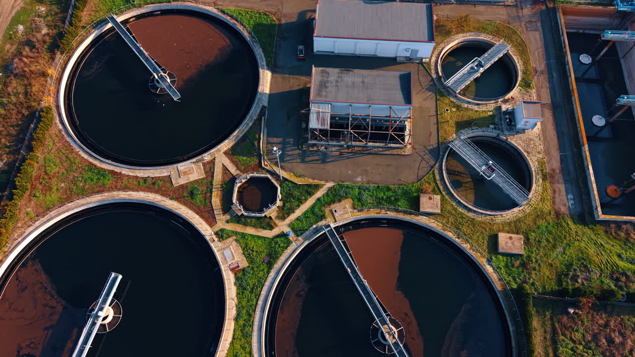Approaching large round reservoirs filled with waste water. Drone footage over the territory of modern sewage recycle plant